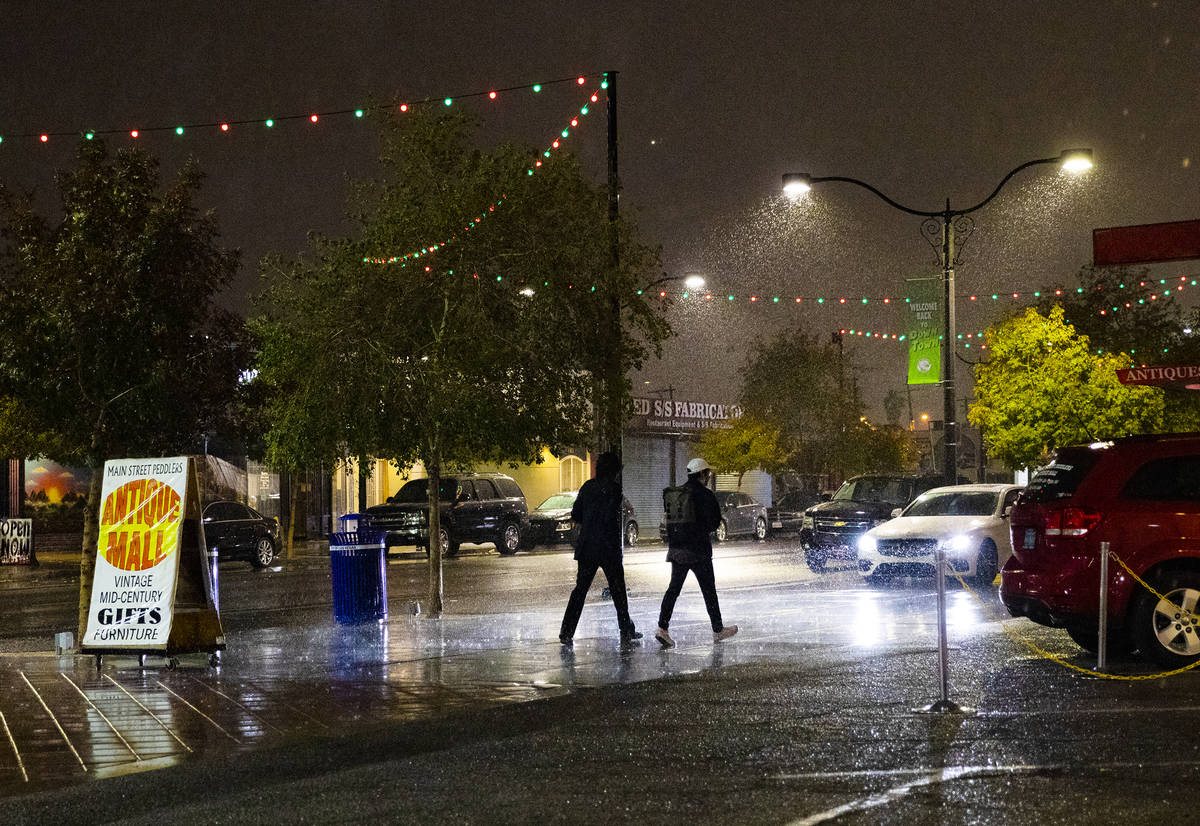 Pedestrians walk through the rain in the Arts District in Las Vegas on Dec. 17, 2020, the first ...