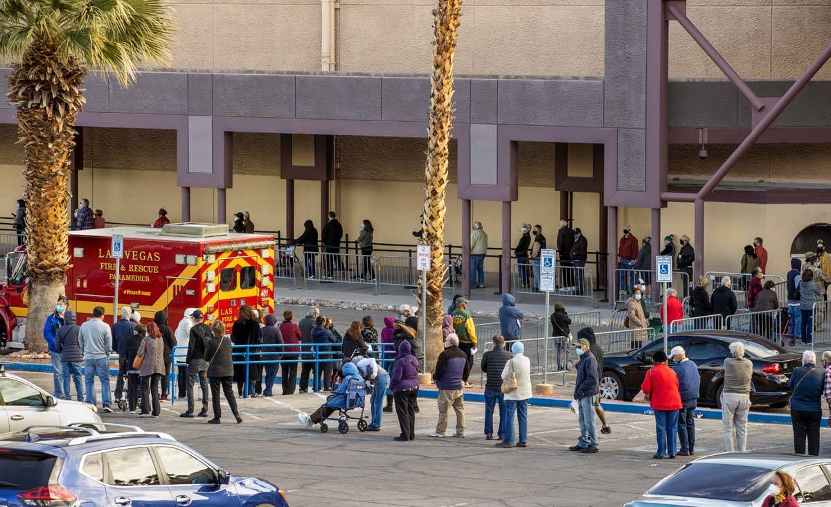 People wait in a long line in the parking lot at the Cashman Center for COVID-19 vaccinations o ...