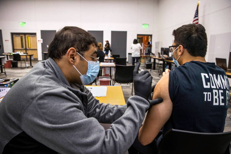 Hugo Peredo, left, with the UNLV School of Medicine, gives a COVID-19 vaccination to CSN studen ...