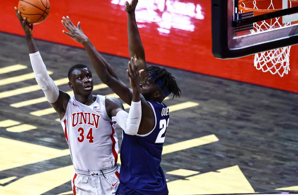 UNLV Rebels forward Cheikh Mbacke Diong (34) shoots around Utah State Aggies center Neemias Que ...