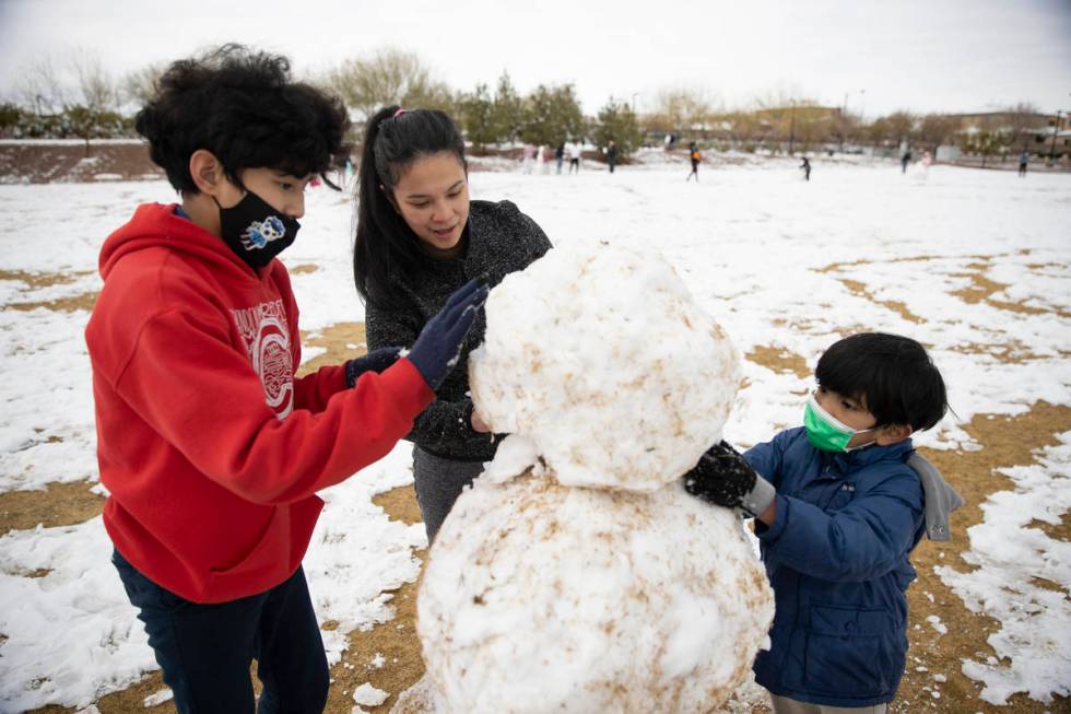 Jenny Lyn Hilario, center, with her sons Gabriel, 12, left, and Isaac, 7, build a snowman at Hu ...