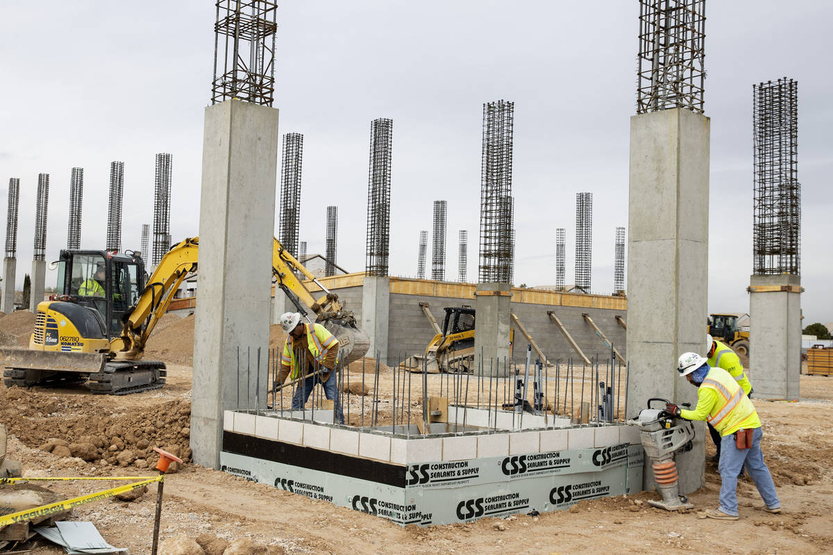 Construction workers use compactors to firm soil at the construction site of Axiom, an office c ...