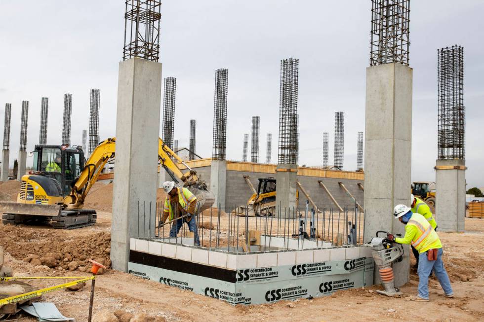 Construction workers use compactors to firm soil at the construction site of Axiom, an office c ...