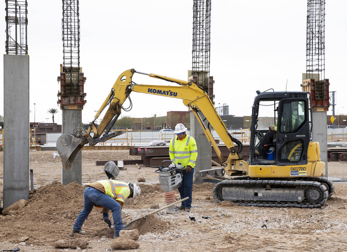 A Construction worker uses compactor to firm soil at the construction site of Axiom, an office ...