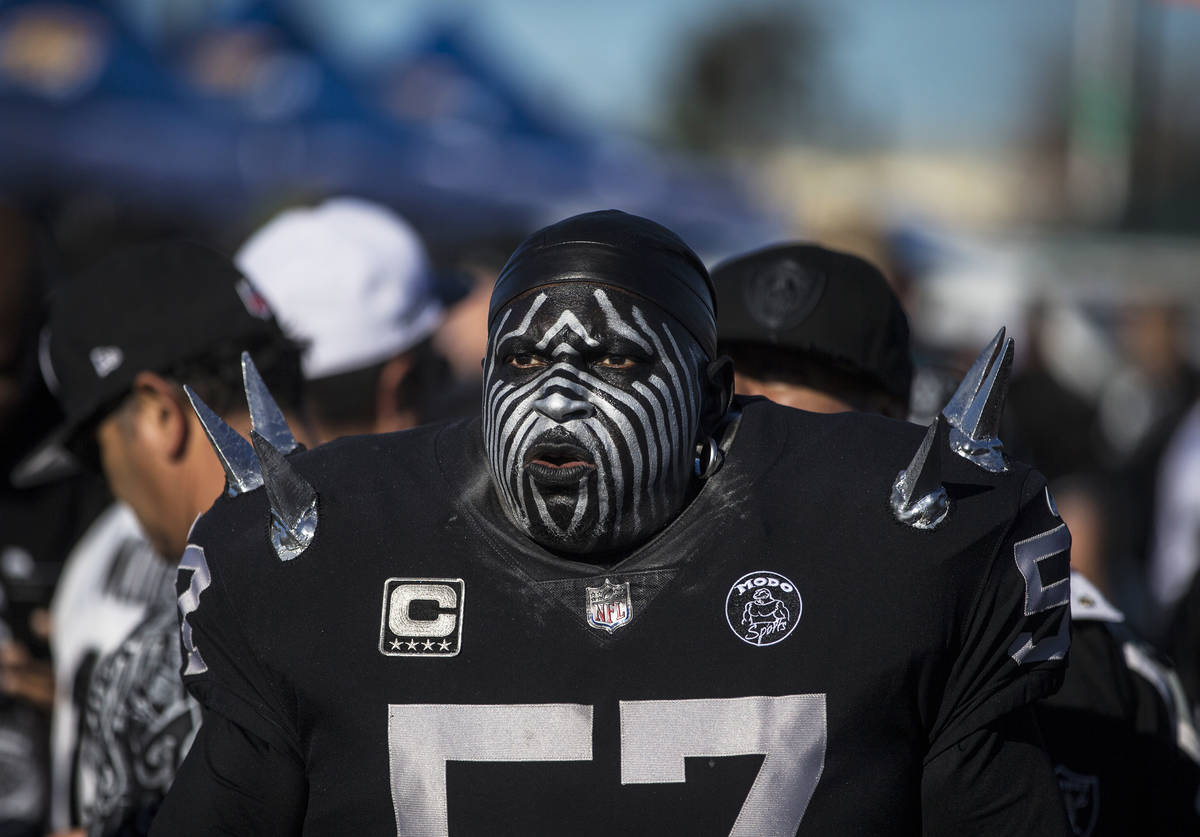 Raiders super fan Wayne Mabry, known as "Violator," walks through a tailgate outside ...