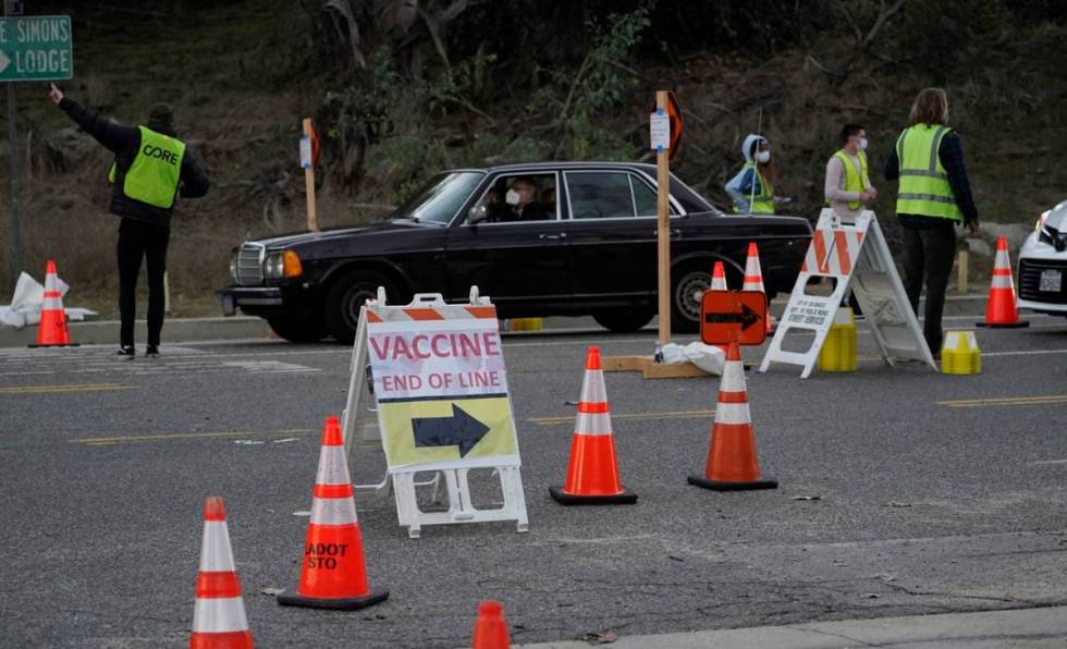 Drivers with a vaccine appointments enter a mega COVID-19 vaccination site set up in the parkin ...