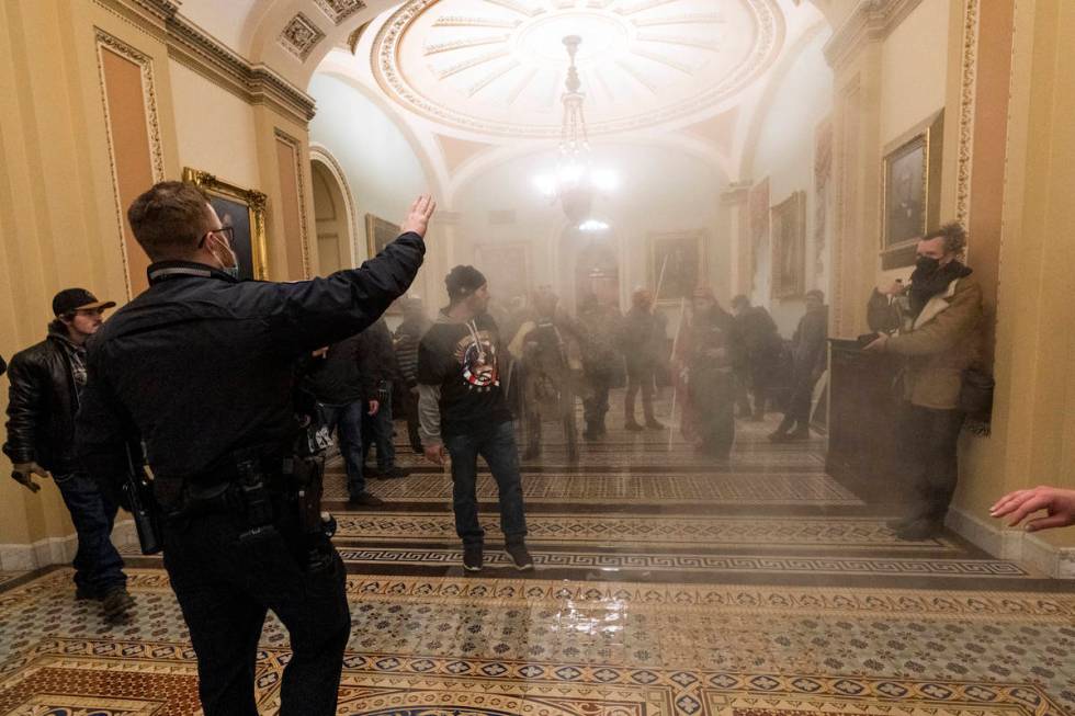 In this Jan. 6, 2021, file photo, smoke fills the walkway outside the Senate Chamber as support ...