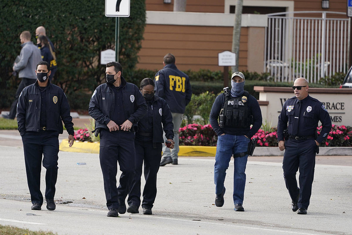 Law enforcement officers walk near the entrance to an apartment complex where a shooting wounde ...