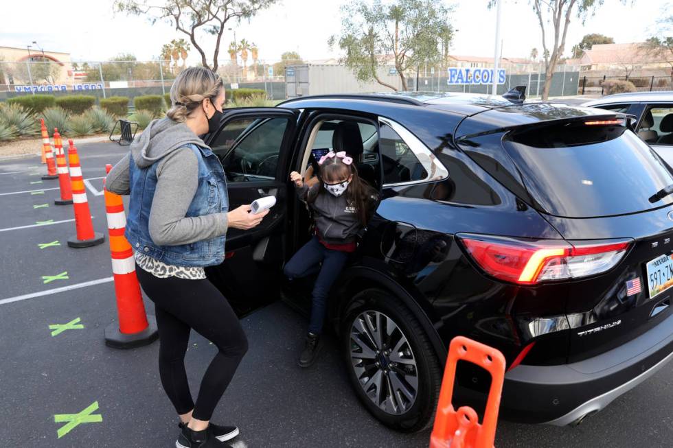 Staff member Amanda Nikolopoulos prepares to take the temperature of student Mason Bachmura, 7, ...