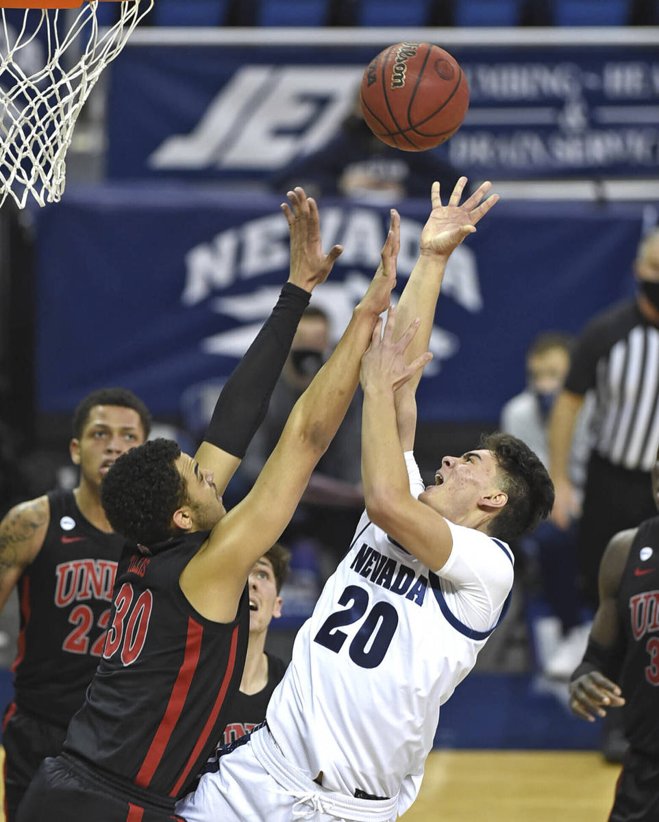 Nevada's Daniel Foster (20) has his shot blocked by UNLV 's Devin Tillis (30) during the second ...
