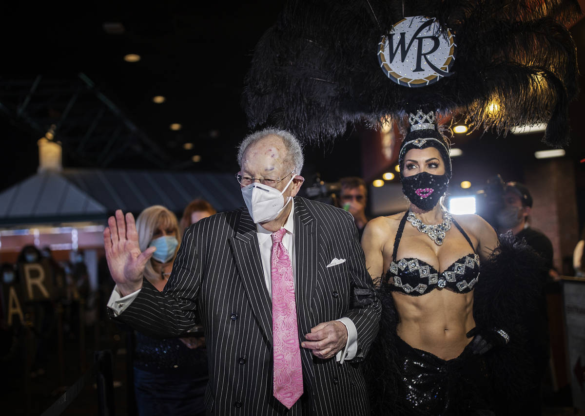 Former Las Vegas Mayor Oscar Goodman, left, is escorted by a showgirl to place his Super Bowl b ...