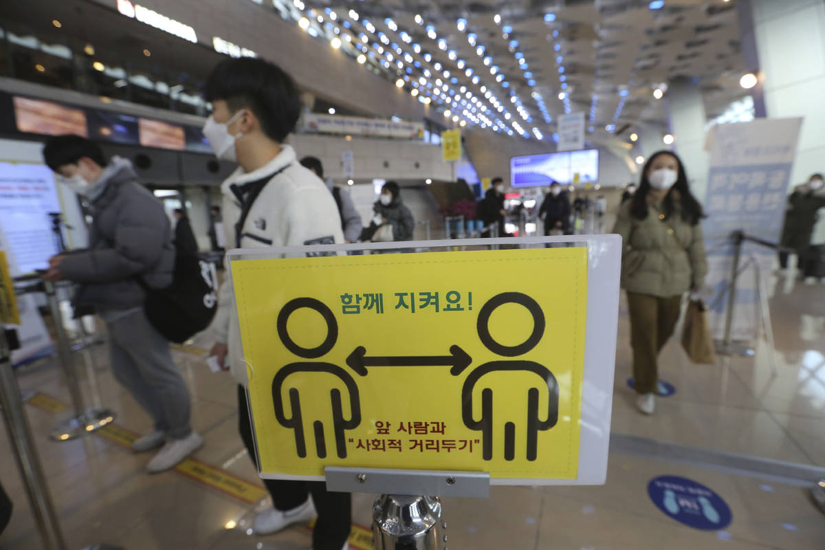A social distancing sign is seen as passengers wait to board planes on the eve of Lunar New Yea ...
