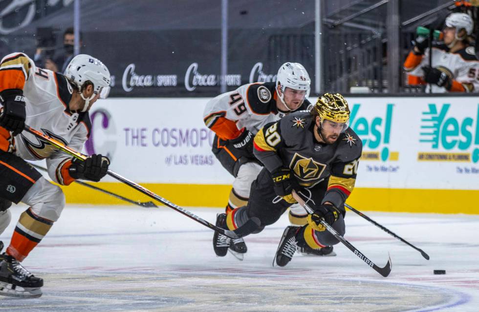 Golden Knights center Chandler Stephenson (20) is tripped up by Anaheim Ducks left wing Max Jon ...