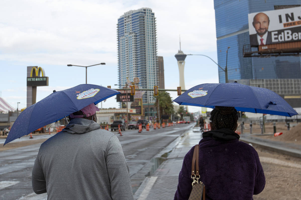 Mary Areh and Tony Areh, of Atlanta, walk north on the Las Vegas Strip while it rains on Friday ...