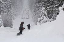 Two men snowboard down a steep street in South Lake Tahoe, Calif., in February 2019. (Ryan Hoff ...