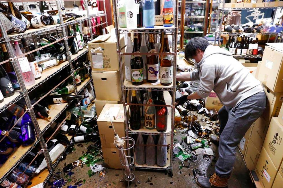 A liquor shop's manager clears the damaged bottles following an earthquake in Fukushima, northe ...