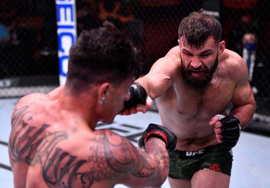 (R-L) Julian Marquez punches Maki Pitolo in their middleweight fight during the UFC 258 event a ...