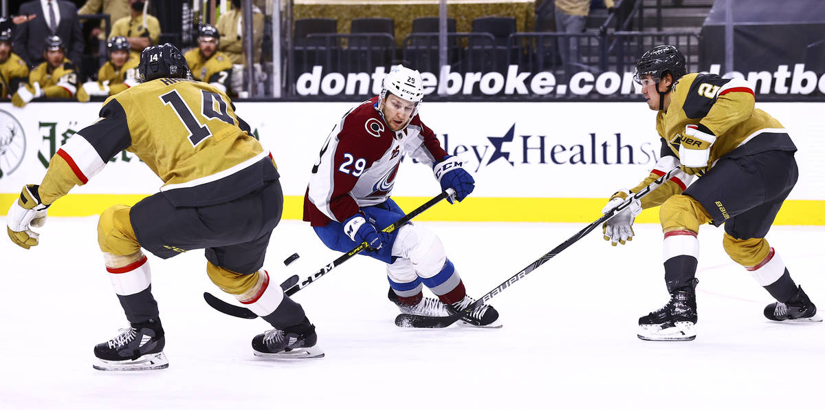Colorado Avalanche center Nathan MacKinnon (29) battles for the puck between Golden Knights def ...