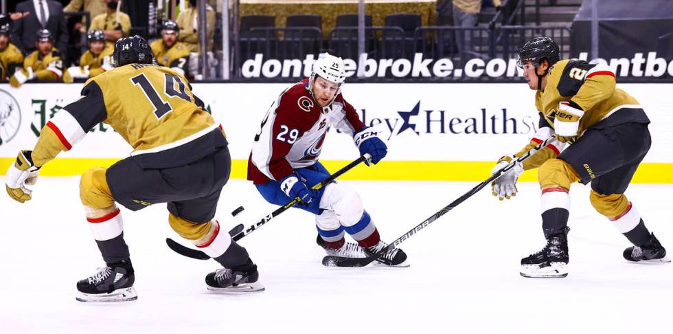 Colorado Avalanche center Nathan MacKinnon (29) battles for the puck between Golden Knights def ...
