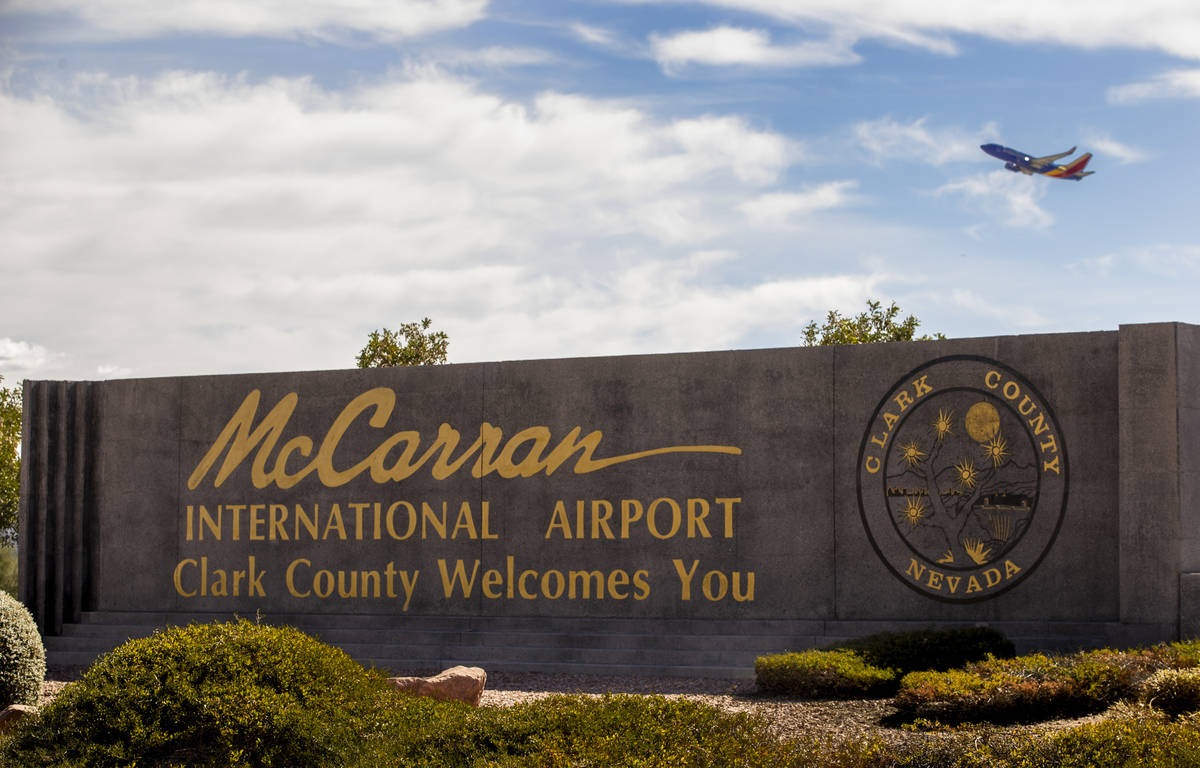 Sign for McCarran International Airport with plane taking off above at Tropicana Avenue and Kov ...