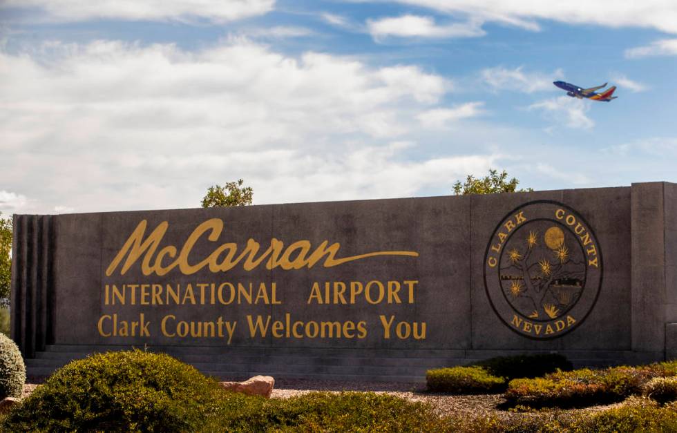 Sign for McCarran International Airport with plane taking off above at Tropicana Avenue and Kov ...