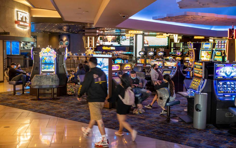 A couple walks through the slots area near the entrance to The Strat as casino floors have move ...