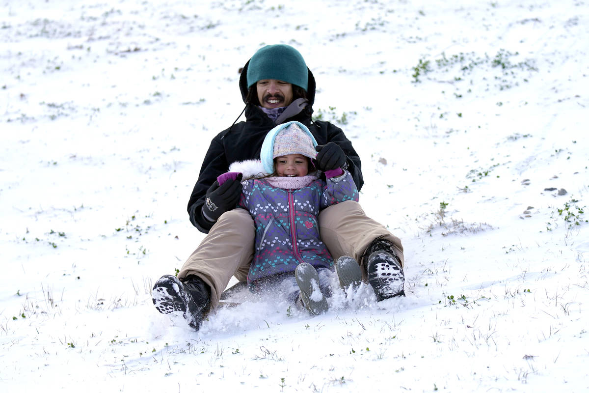Robert Savannah and his daughter Sophia, 4, slide down a snow covered hill Monday, Feb. 15, 202 ...