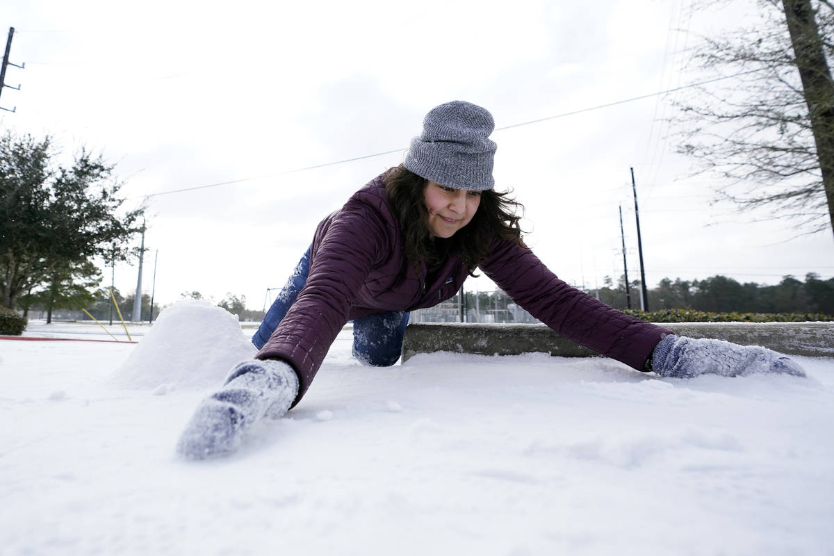 Cristina Lucero gathers snow while trying to build a snowman Monday, Feb. 15, 2021, in Houston. ...
