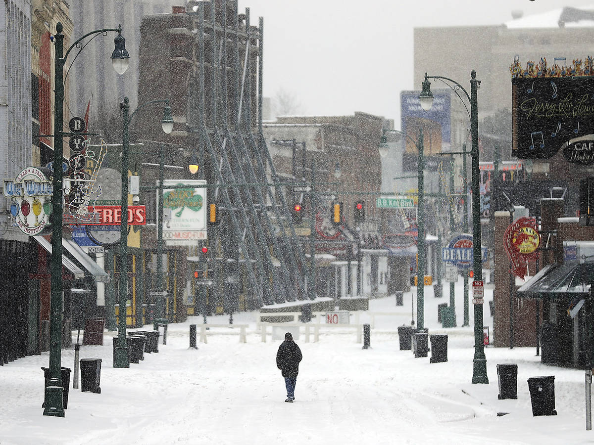 A lone man walks down the center of a snowy Beale Street in Downtown Memphis, Tenn., Wednesday, ...