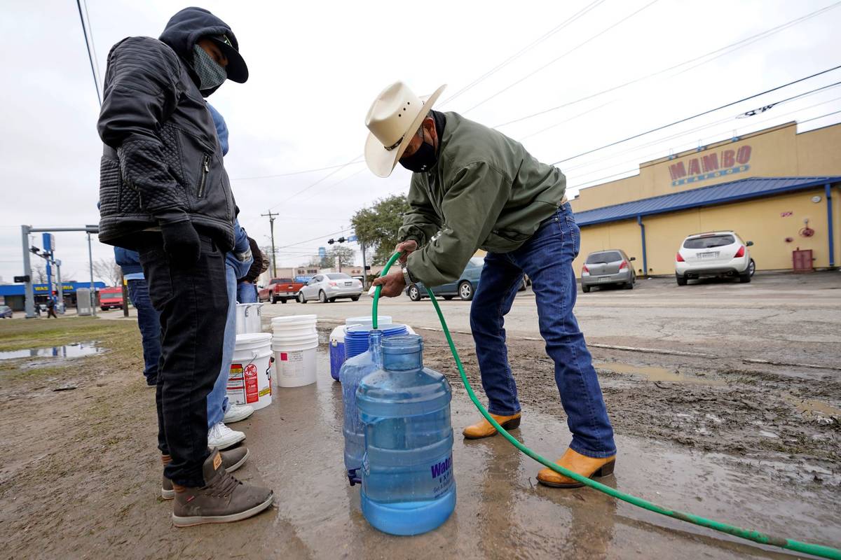 Leovardo Perez, right, fills a water jug using a hose from a public park water spigot Thursday, ...