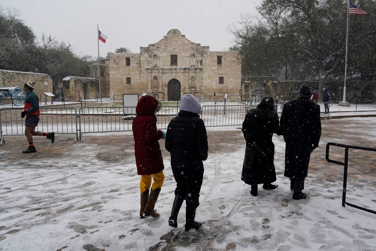 People walk through the snow as they pass the Alamo, Thursday, Feb. 18, 2021, in San Antonio. ...