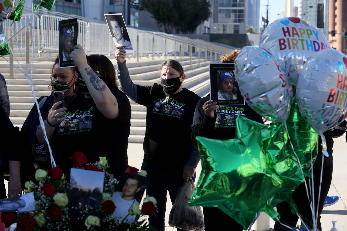 Carol Luke, center, holds a photo of Jorge Gomez, a Black Lives Matter protester who was shot a ...