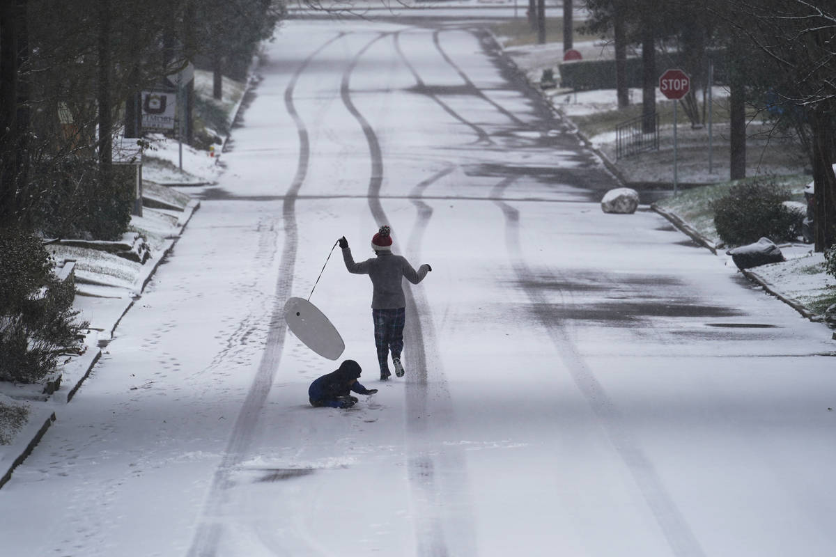 Children play with a sled as snow begins to accumulate, Thursday, Feb. 18, 2021, in San Antonio ...