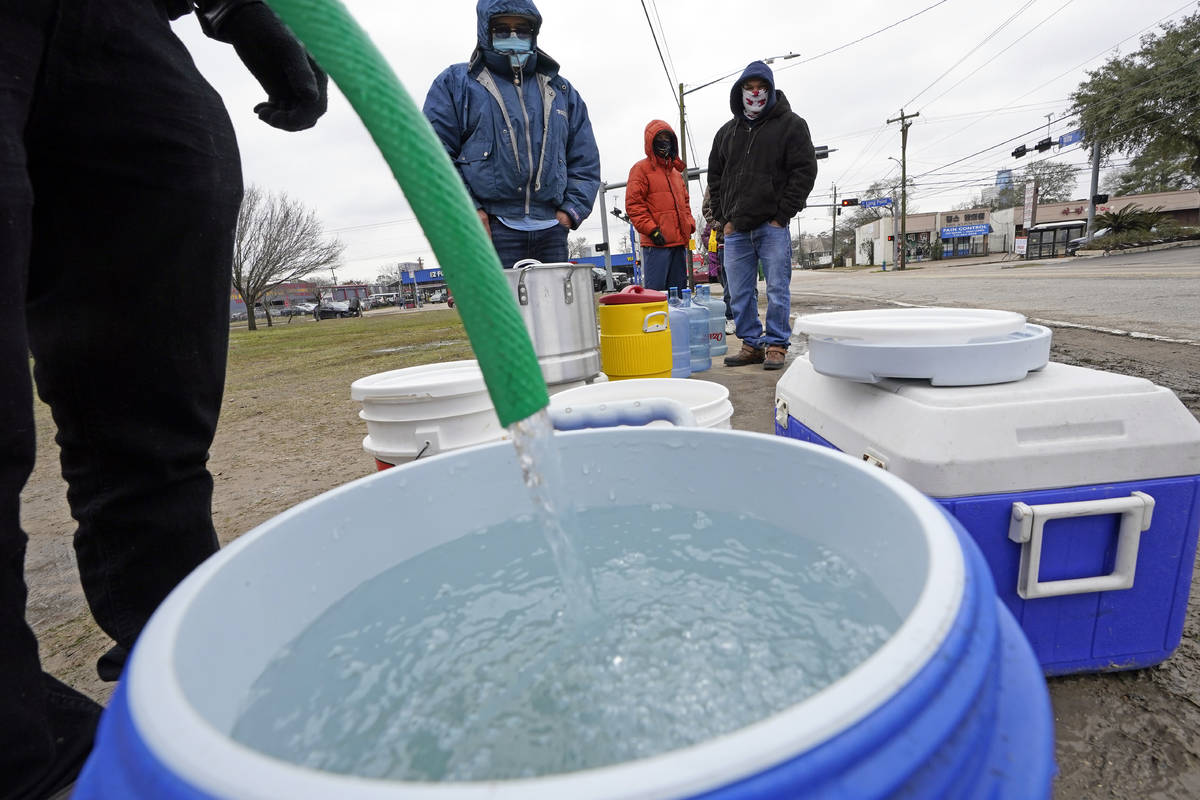 A water bucket is filled as others wait in near freezing temperatures to use a hose from public ...