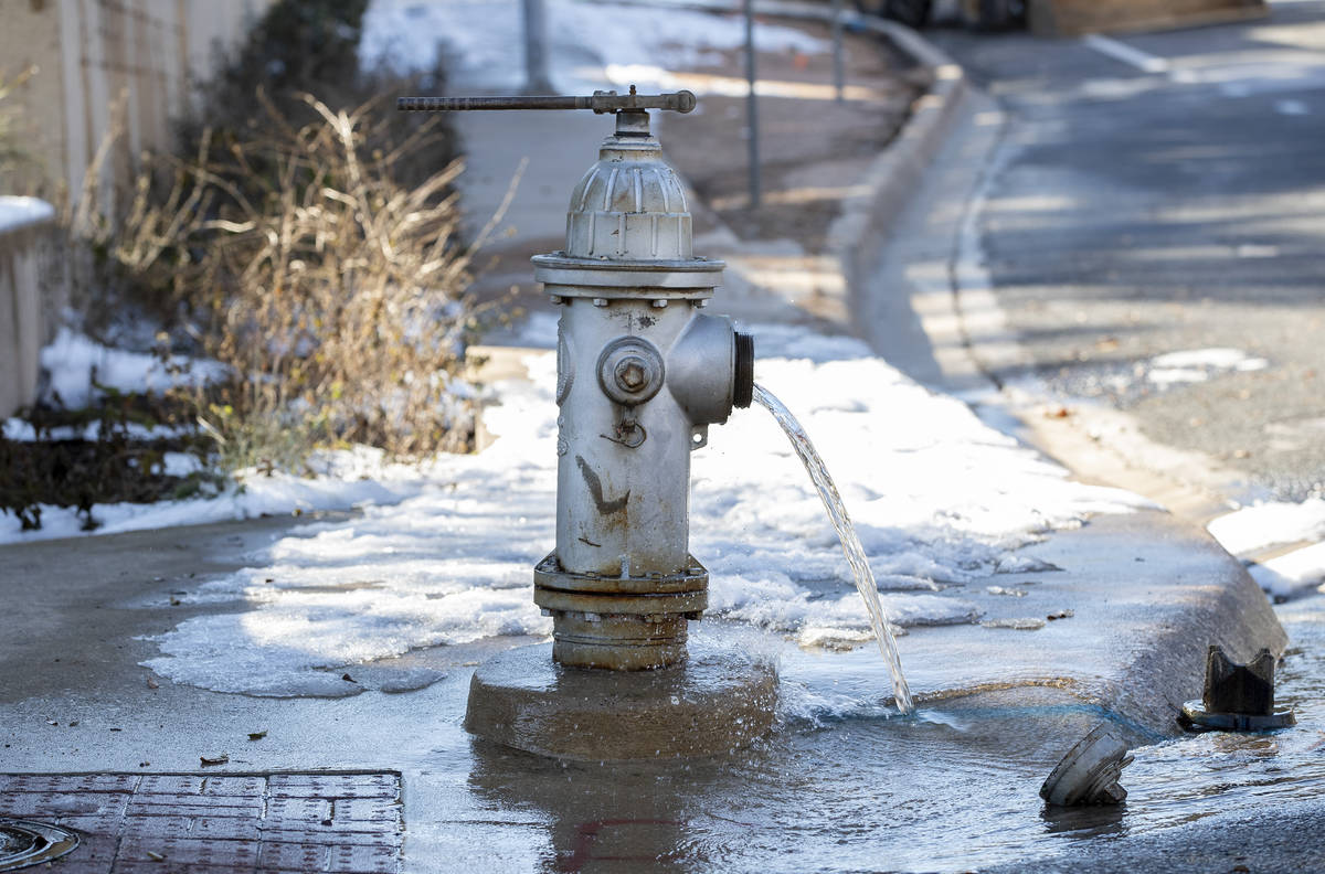 Water trickles from a fire hydrant while City of Austin Water Utility workers repair a broken w ...