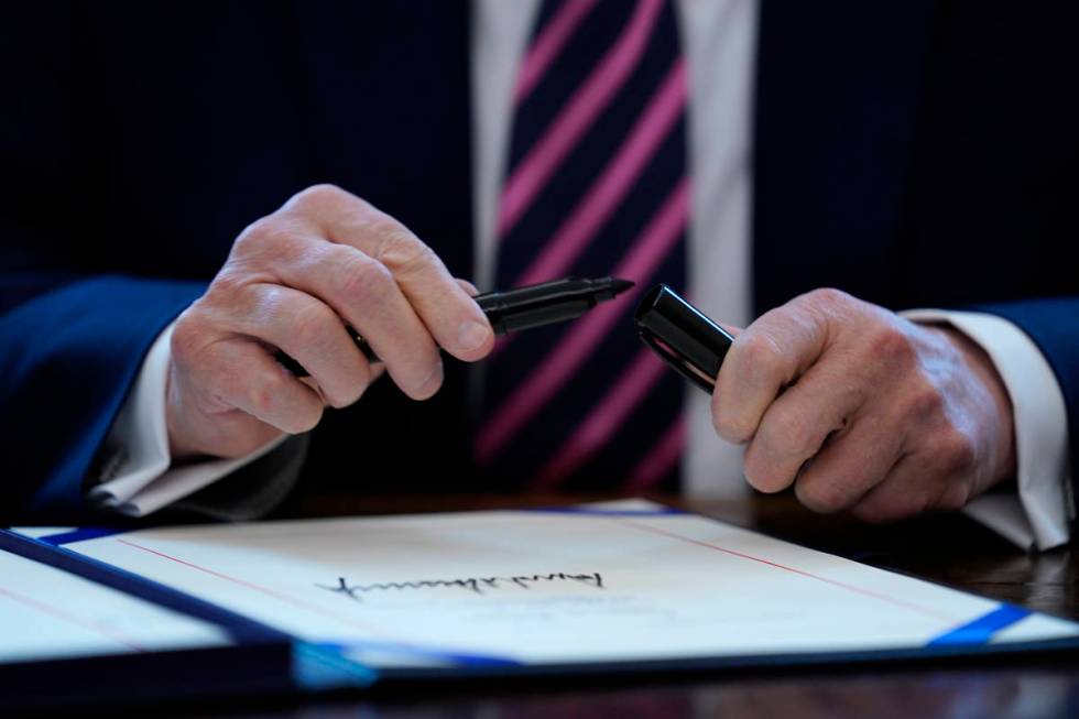 FILE - In this April 24, 2020, file photo President Donald Trump puts the cap on a pen after si ...