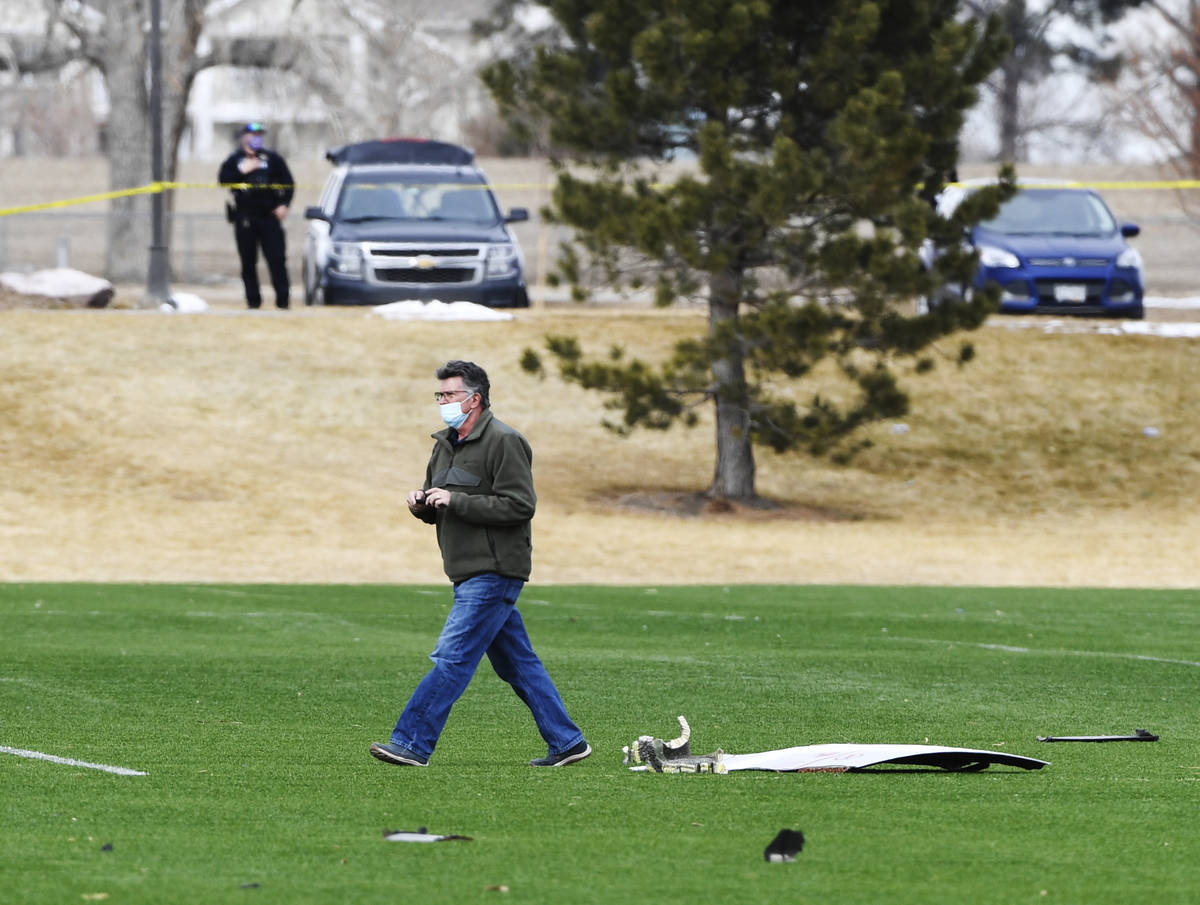 A man walks past airplane parts scattered on a soccer field at Broomfield Commons Park, Saturda ...