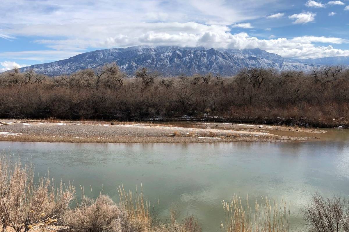 The Rio Grande flows through Rio Rancho, New Mexico, as snow covers the Sandia Mountains in Feb ...