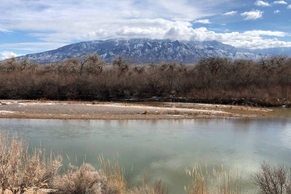 The Rio Grande flows through Rio Rancho, New Mexico, as snow covers the Sandia Mountains in Feb ...