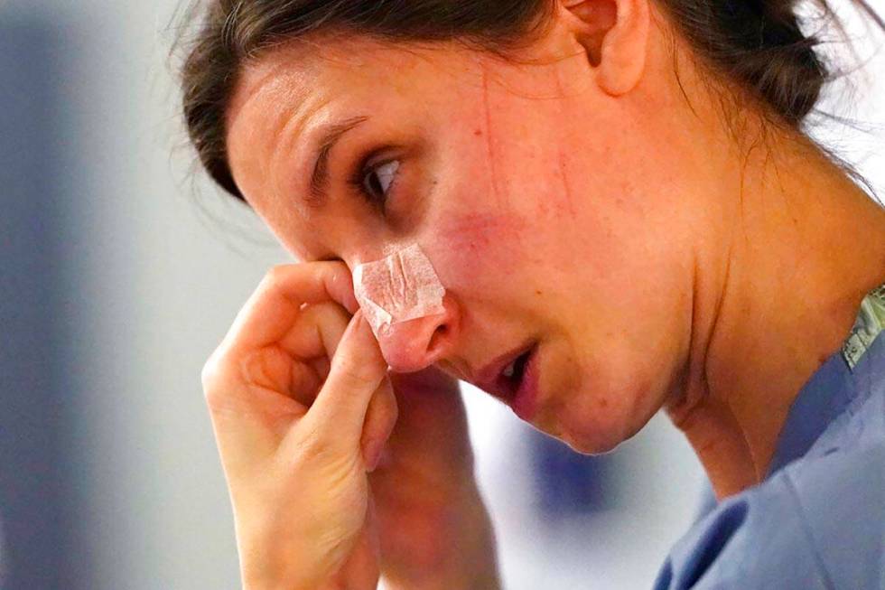 In this Jan. 26, 2021, file photo, with indentations from a N-95 mask marking her face, registe ...
