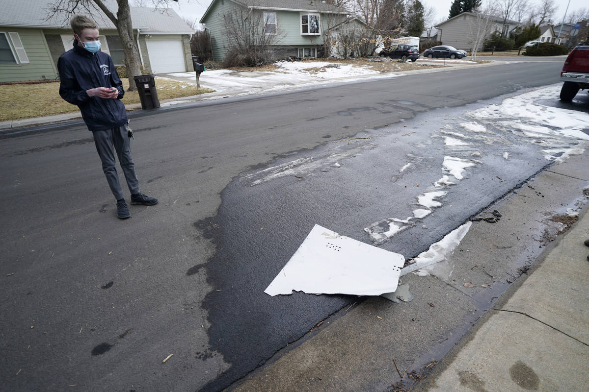 A man looks over debris that fell off a plane as it shed parts over a neighborhood in Broomfiel ...