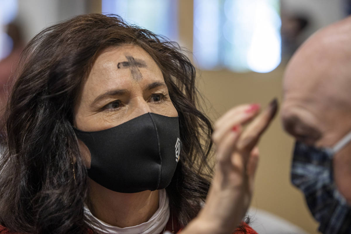 Shelley Flandermeyer places ashes in the sign of a cross on husband MattÕs forehead during ...