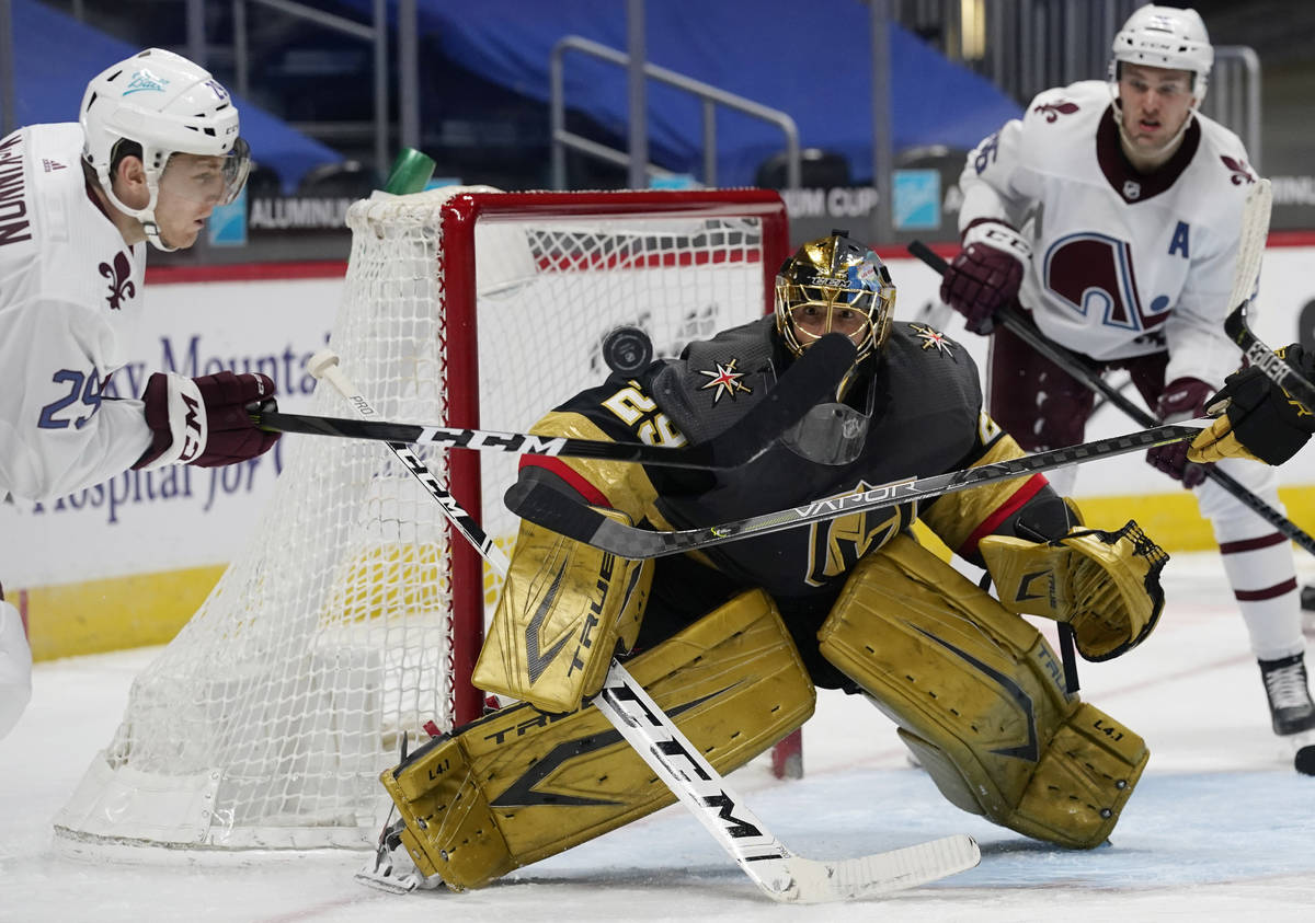 Colorado Avalanche center Nathan MacKinnon, left, swings at the puck as Vegas Golden Knights go ...