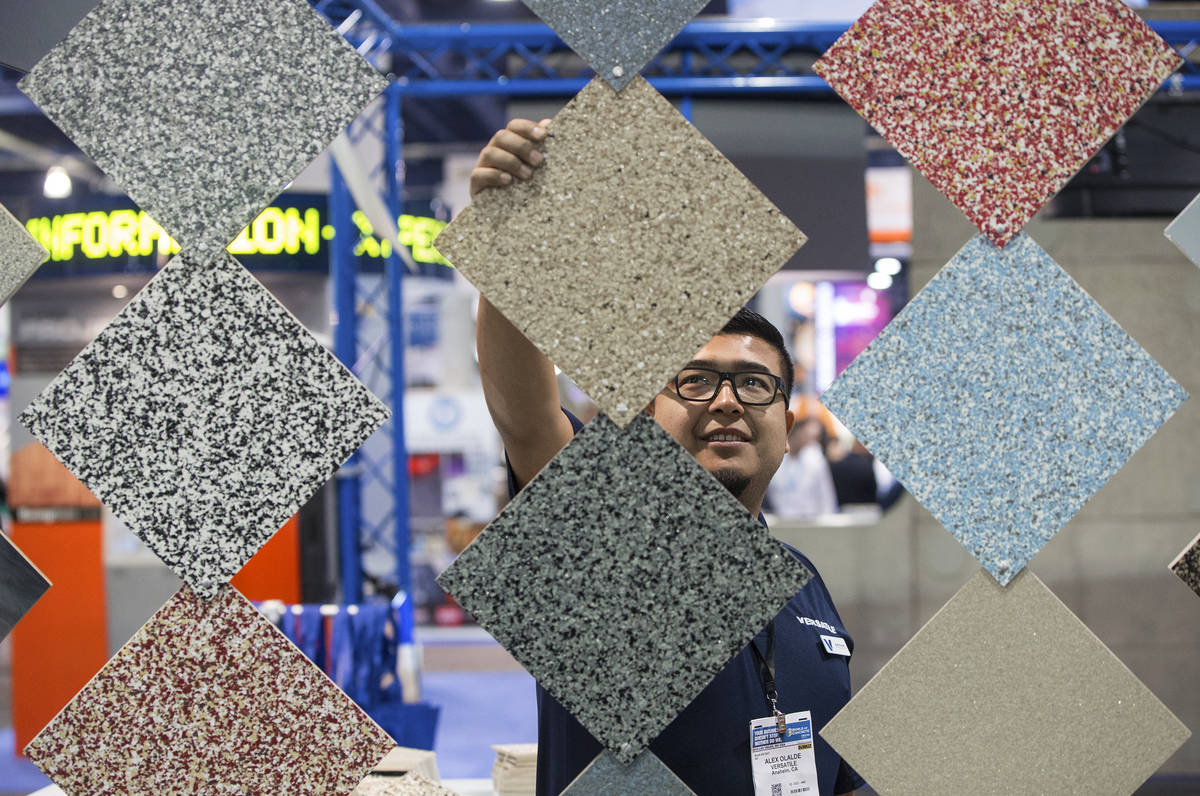 Alex Olalde, a sales representative with Versatile, straightens tiles at his booth during day t ...