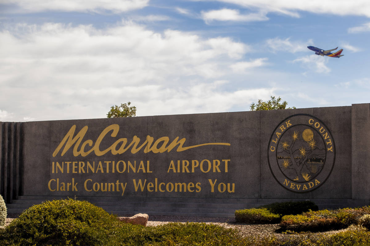 Sign for McCarran International Airport with plane taking off above at Tropicana Avenue and Kov ...