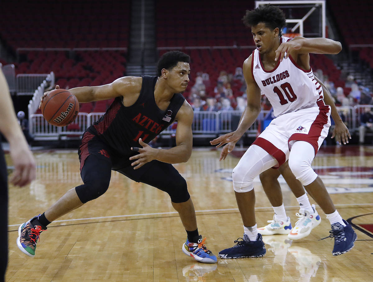 San Diego State's Matt Mitchell looks for room to drive past Fresno State's Orlando Robinson du ...