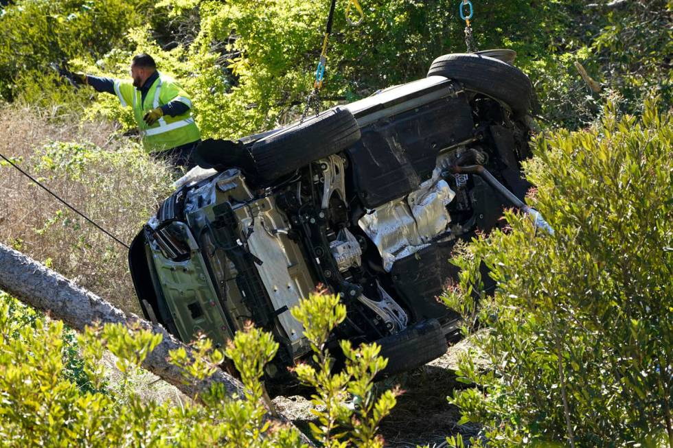 Workers move a vehicle on its side after a rollover accident involving golfer Tiger Woods Tuesd ...