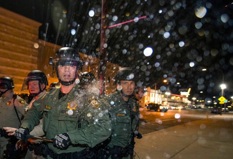 A Las Vegas police officer is struck on the shoulder by a water bottle during clashes with prot ...