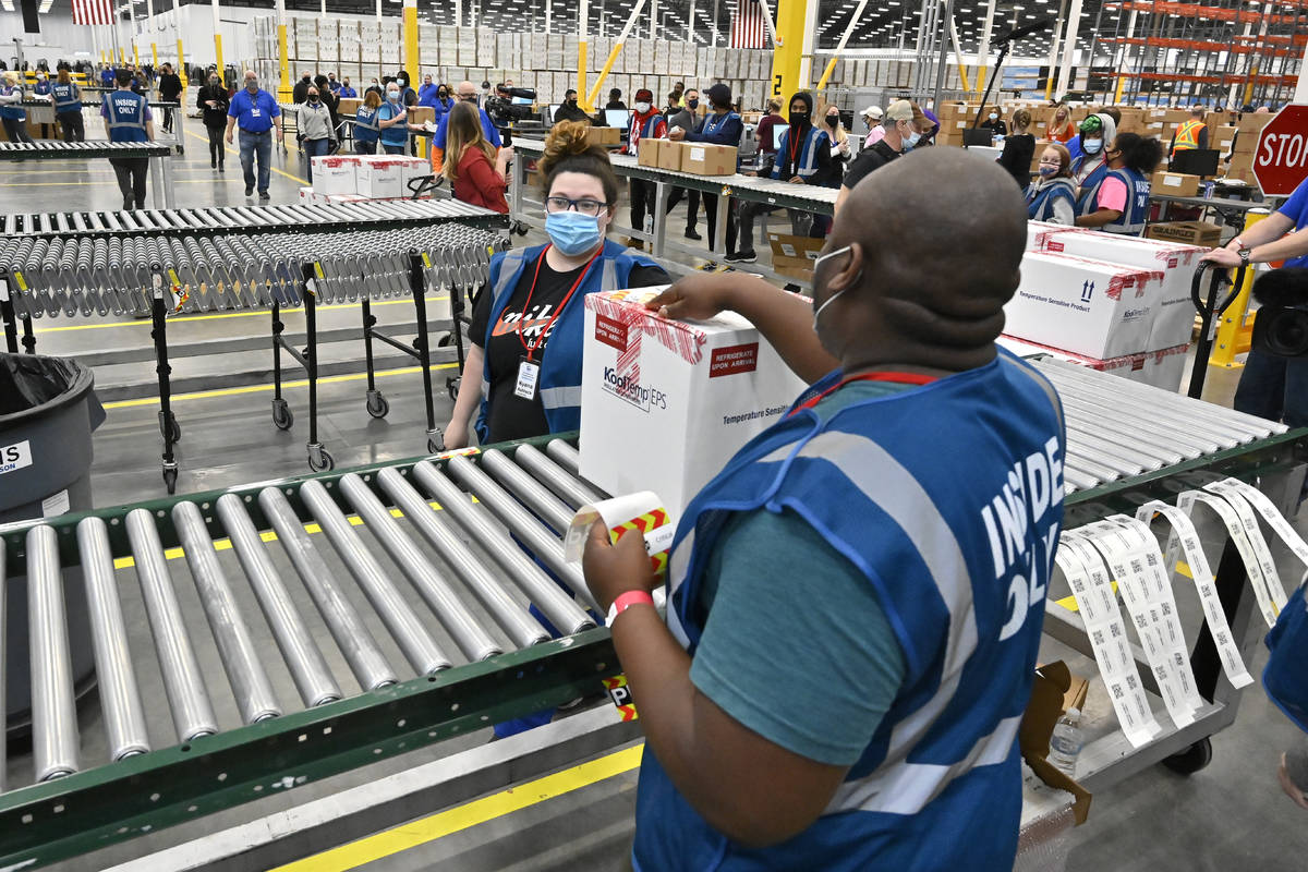 The first box containing the Johnson & Johnson COVID-19 vaccine heads down the conveyor to ...