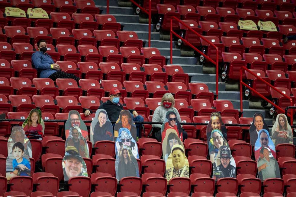 Fans sit in distanced seats during the second half of an NCAA men's basketball game between the ...